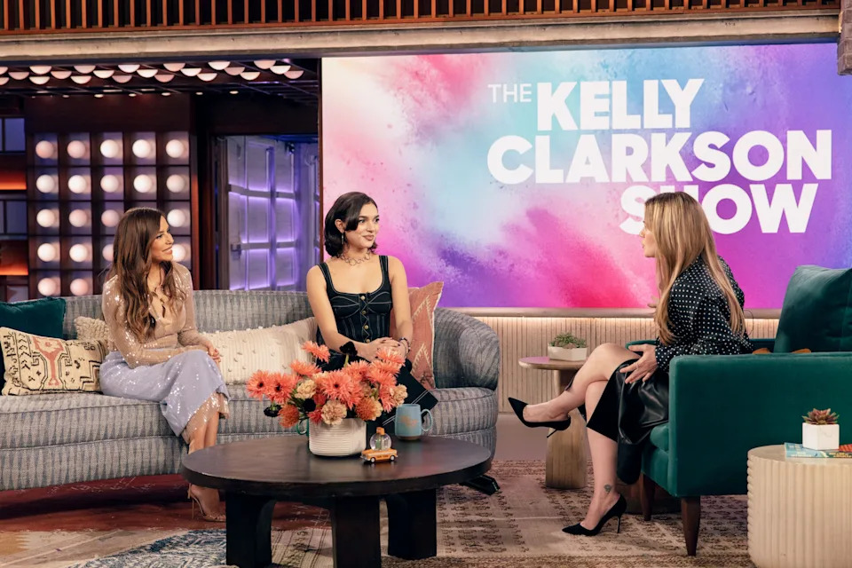Eva Longoria, Paulina Chavez, and Kelly Clarkson are seated on a talk show set with "The Kelly Clarkson Show" logo displayed on a screen behind them