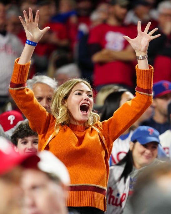 kate upton cheering with her arms in the air at world series game