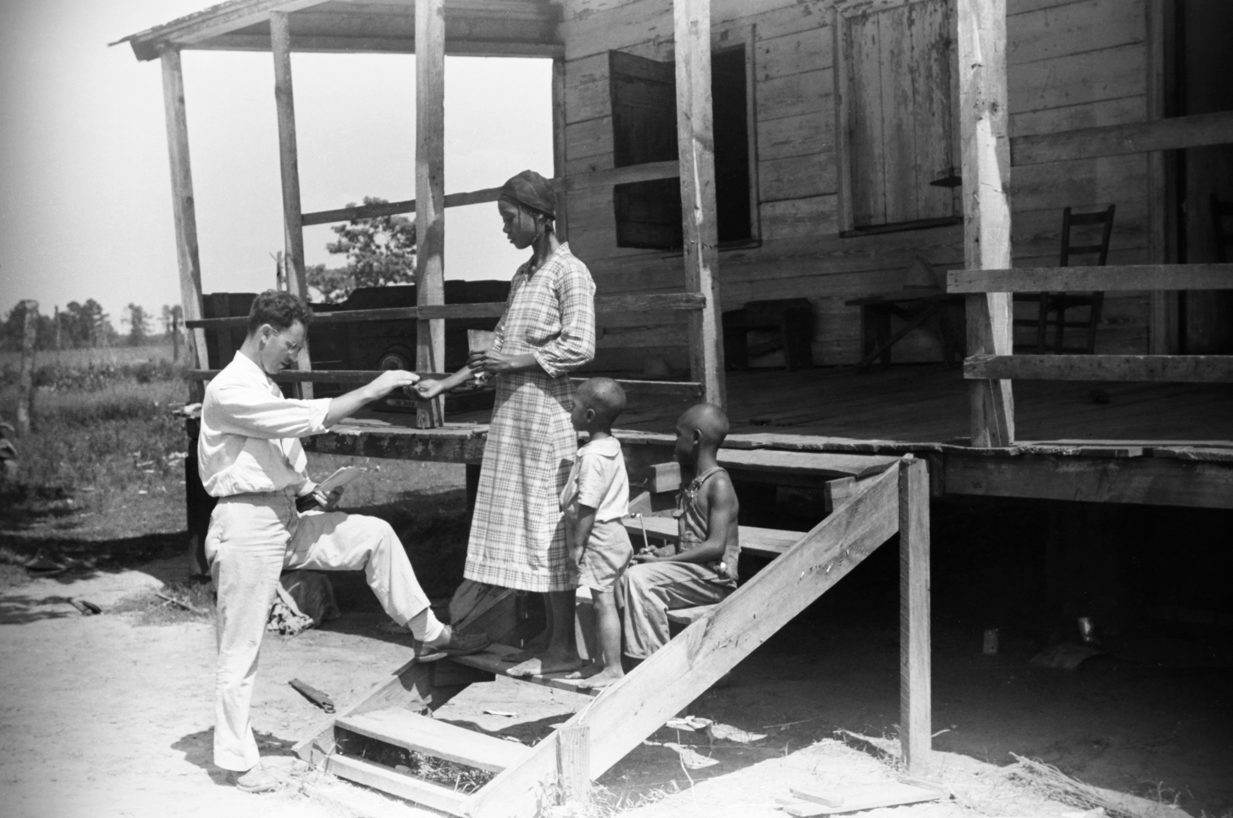 A public health doctor giving a Black family malaria medicine in South Carolina circa June 1939.