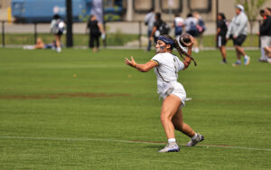 A person in a white sports uniform throwing a football on a grassy field.
