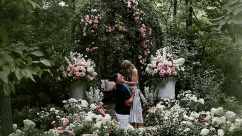 @TaylorSwift/Instragram Travis Kelce gets on one knee to pop the question to Taylor Swift surrounded by an abundance of flowers. 