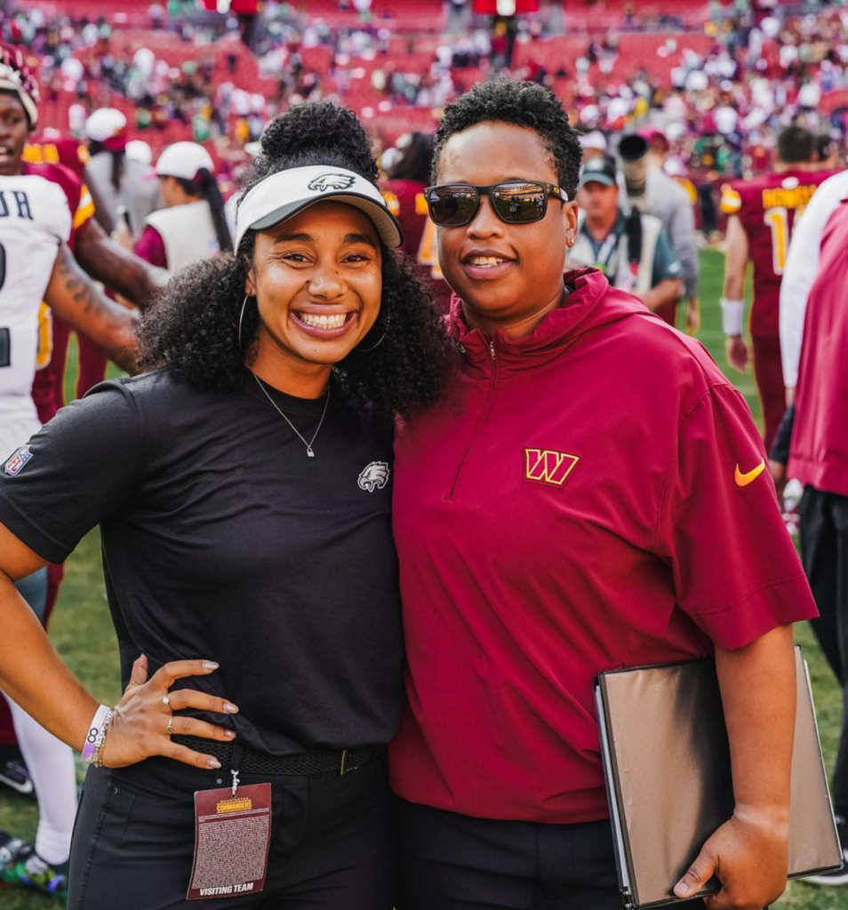 A coach and a staff member smiling on a football field