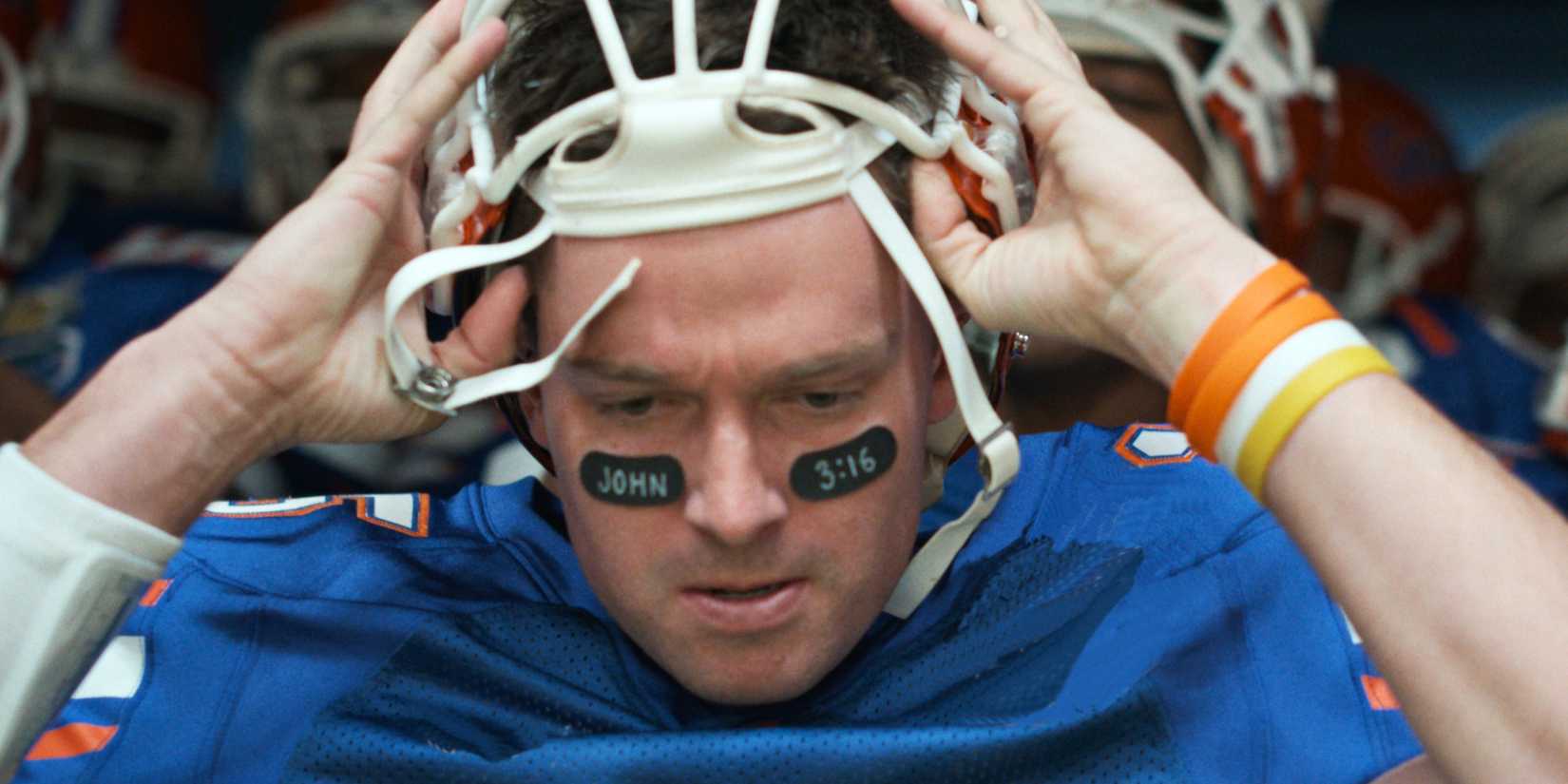 Patrick Schwarzenegger as Tim Tebow with his helmet and a Bible quote on his face in American Sports Story