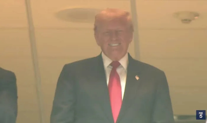 Man in suit with a red tie, smiling, stands indoors at an event. FOX 5 logo in corner
